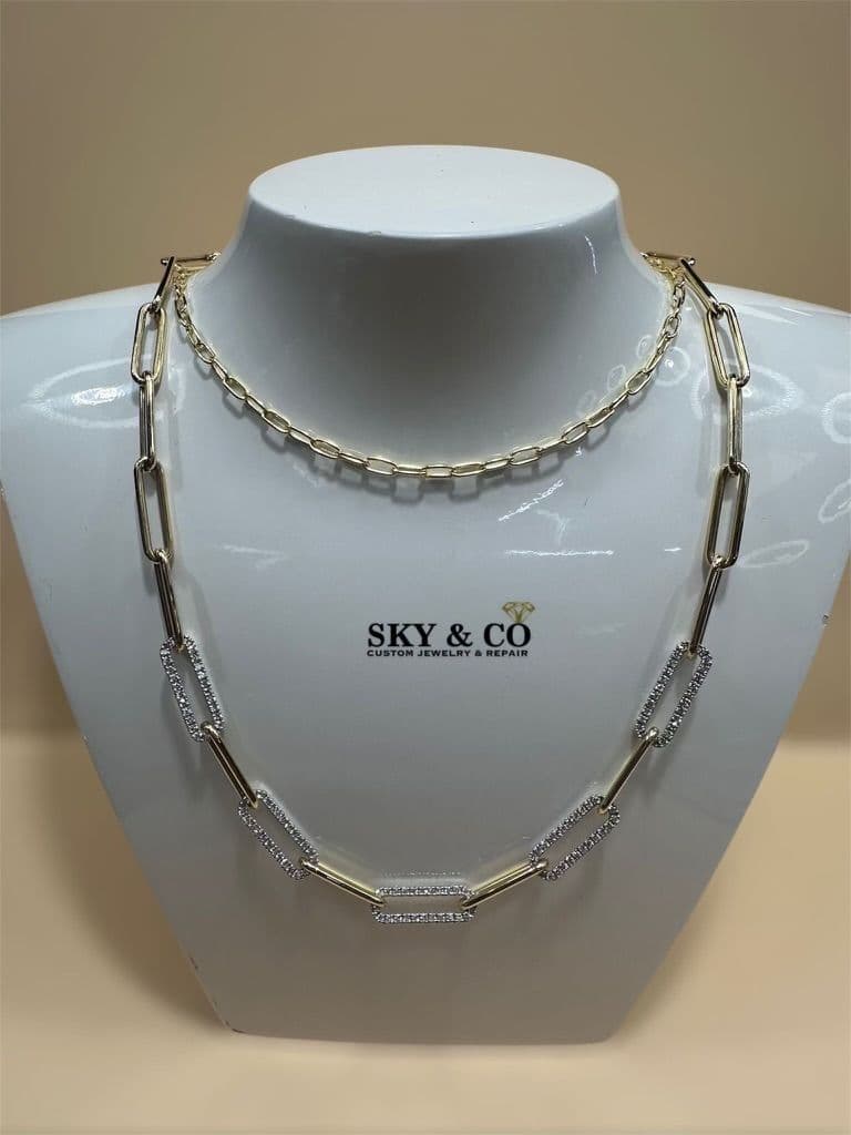 Two layered gold and diamond necklaces on a bust