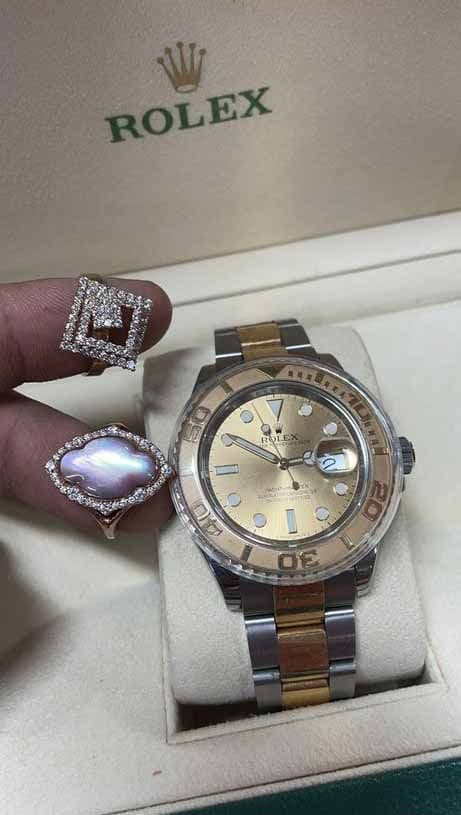 A two-tone Rolex Yacht-Master watch next to two diamond rings