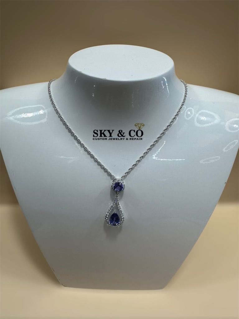 A custom sapphire and diamond drop necklace on a bust